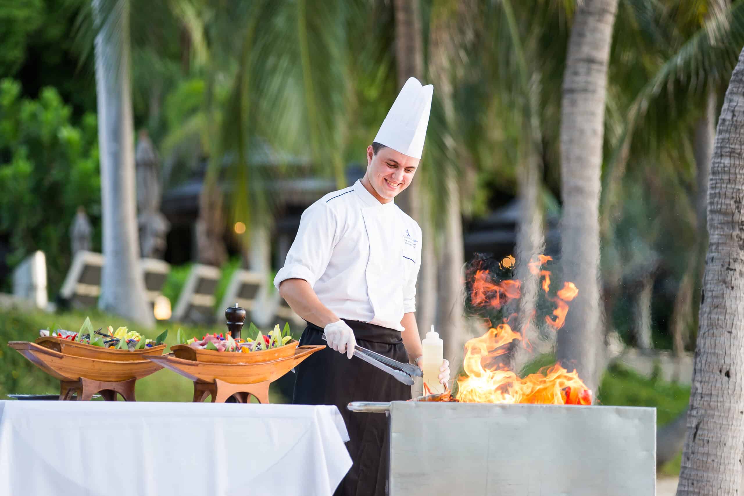chef preparing food on grill for beach dinner