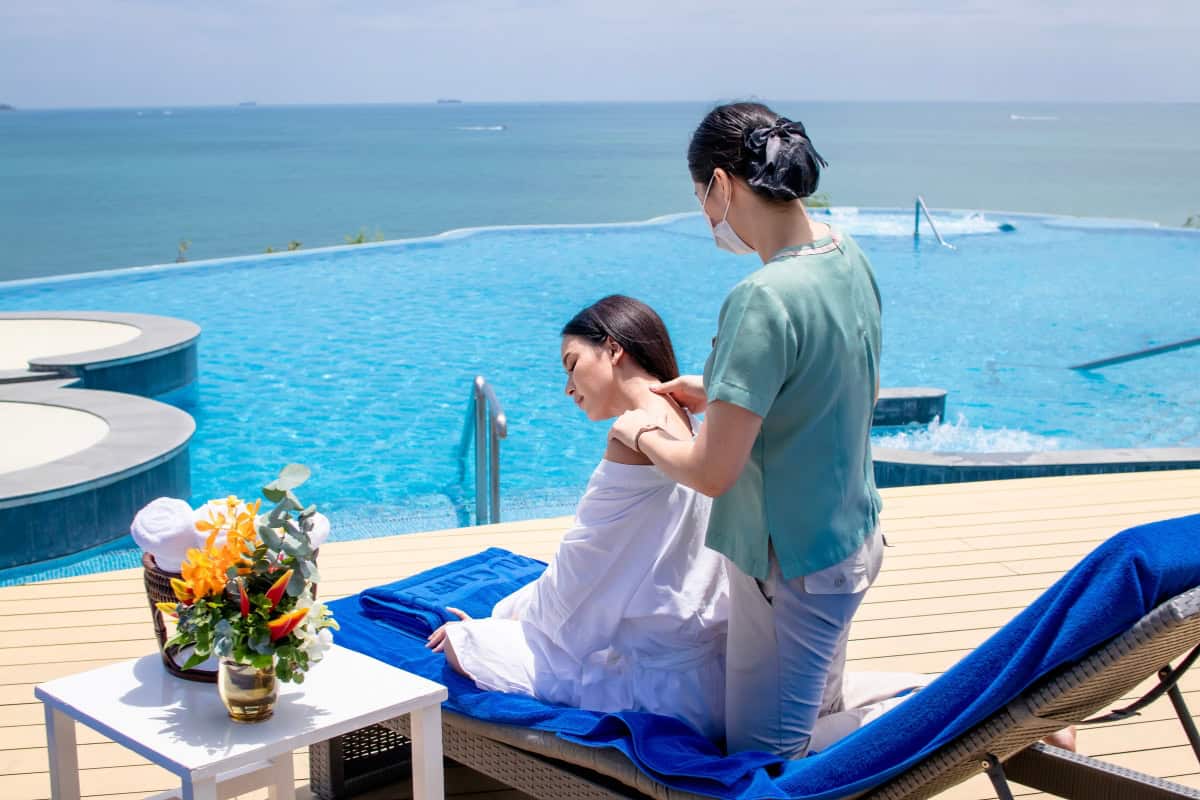 customer getting a massage by the hotel swimming pool overlooking the ocean